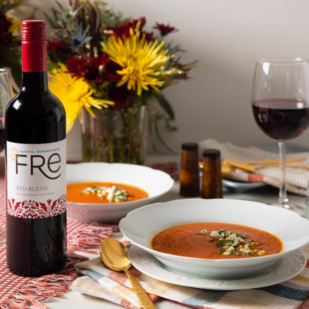 Table setting with Fre red blend wine, bowls of soup, and a glass of wine.