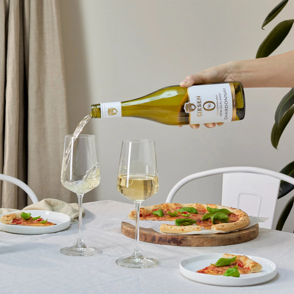 Giesen Chardonnay being poured into a glass with pizza on table