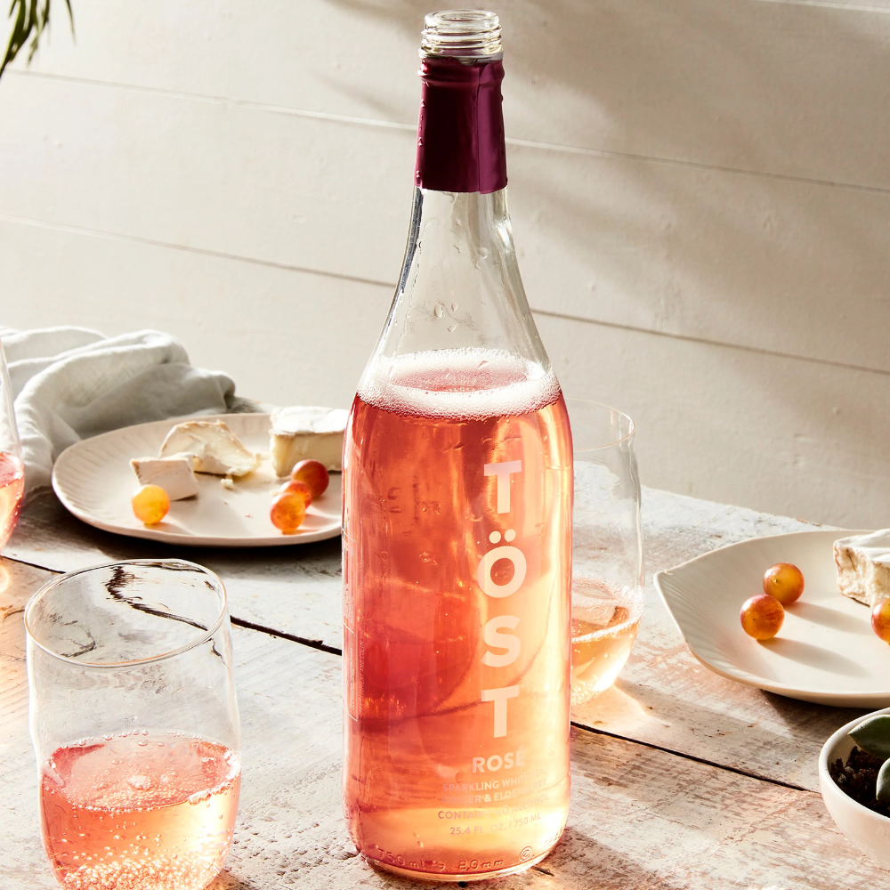 Bottle of Töst Rosé wine on a table with glasses and plates in the background