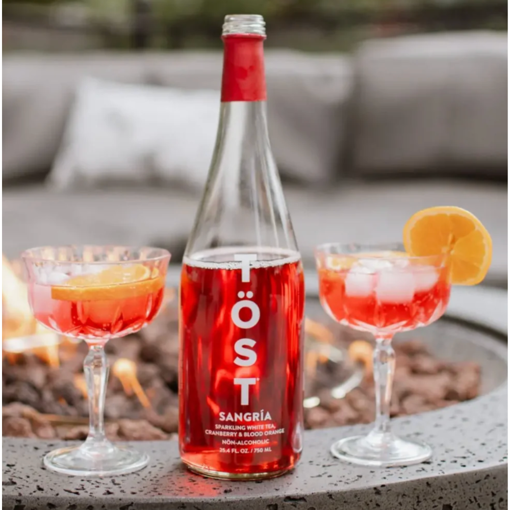 Tost sangria poured into two glasses with orange