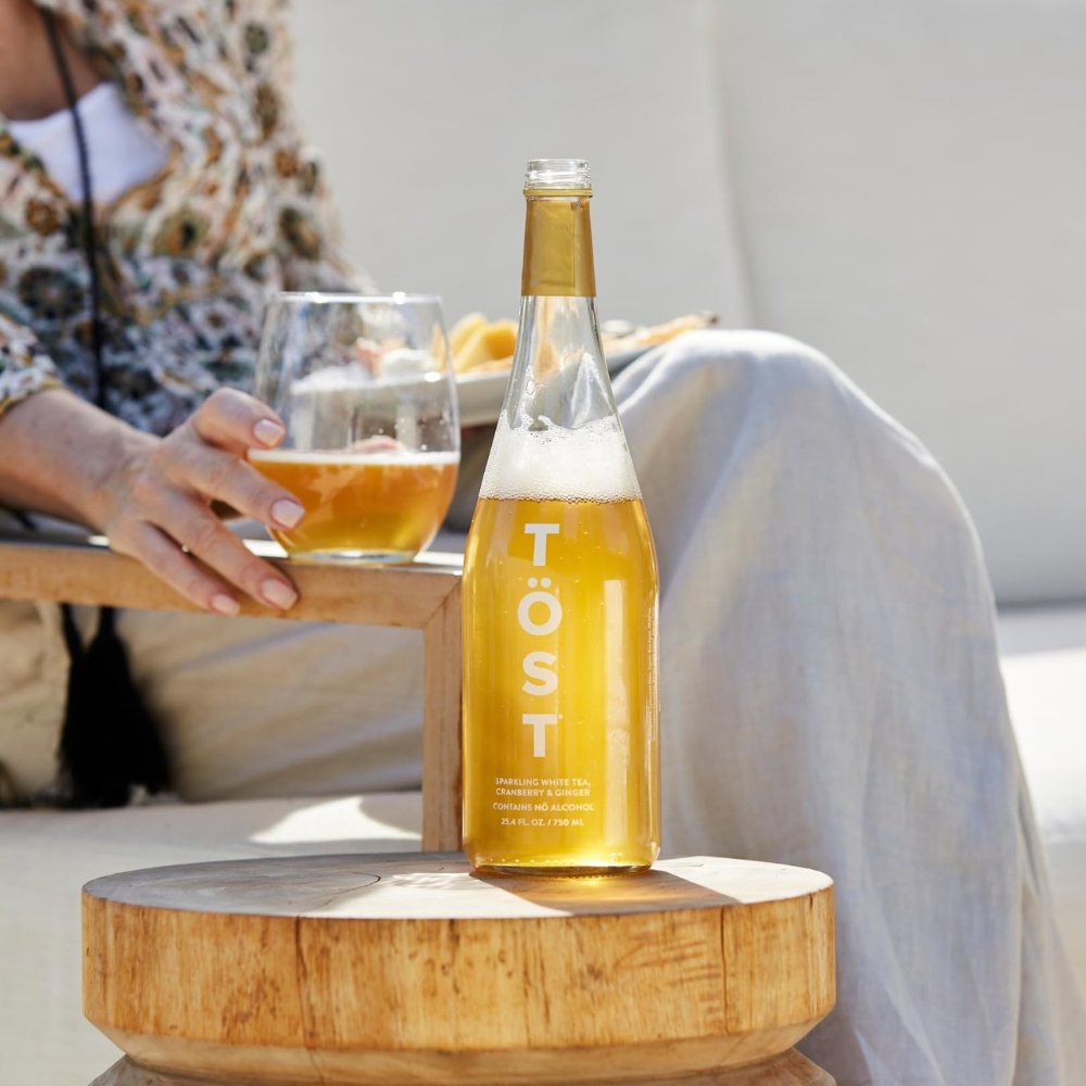 Tost Sparkling white tea poured into a glass with women holding the glass
